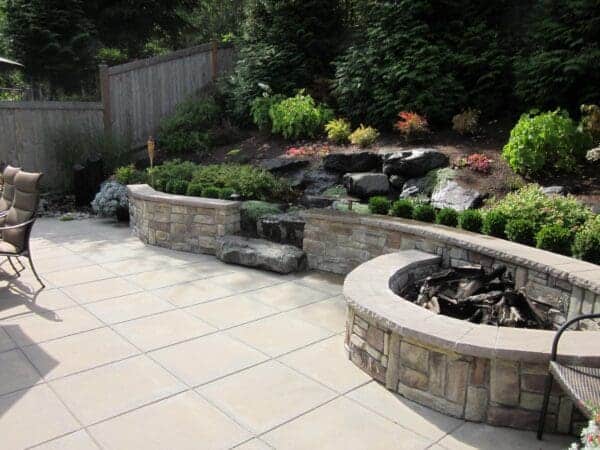 Natural stone fire pit in residential backyard for article on Terraced Gardens: Beautiful Solutions for Slope Yards