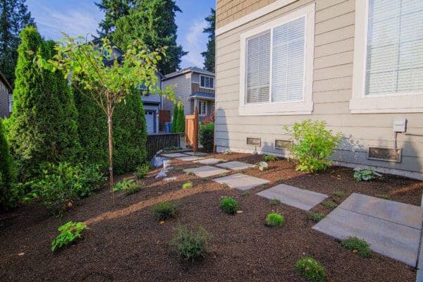 Backyard patio with surrounding garden beds and ornamental plantings in Kirkland landscape design project