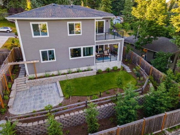 Custom stone patio outdoor living area with furniture and shade structure in Kenmore residential landscape design