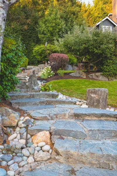 Mature ornamental plantings bordering maintained lawn with lake views in Greater Seattle residential landscape