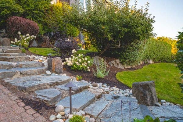 Garden terrace with native Pacific Northwest plantings and natural stone accents overlooking lake in Seattle area