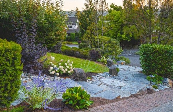 Residential garden design integrating mature trees and perennial beds with water view in Greater Seattle