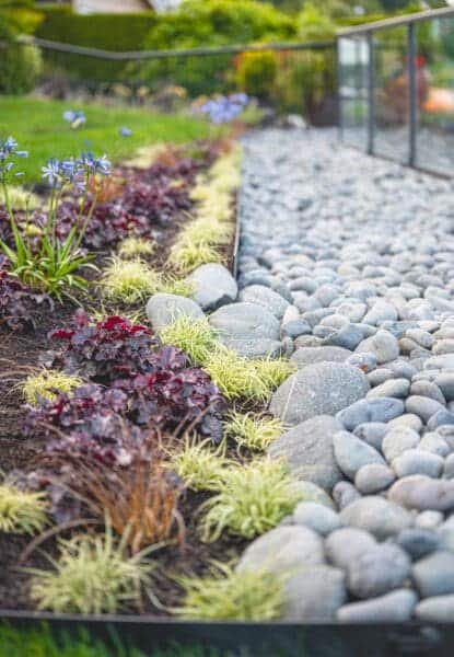 Lakefront Landscape featuring mature trees and stone pathways by Classic Landscaping