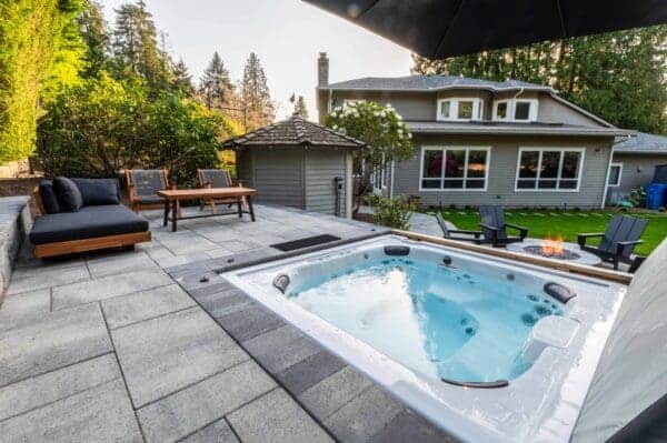 Slate paver patio with embedded hot tub and lounge area in Shoreline WA peaceful backyard retreat by Classic Landscaping