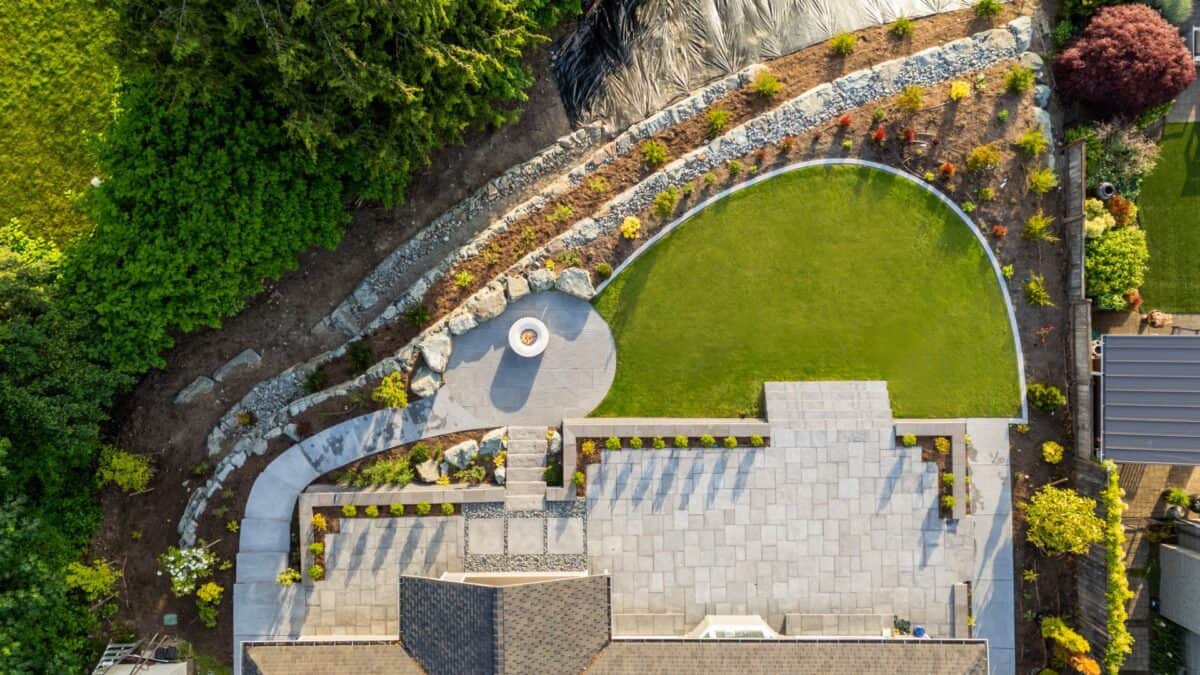 Private master bedroom patio with concrete walkway and evergreen screen plantings overlooking Lake Washington in Kenmore landscape design
